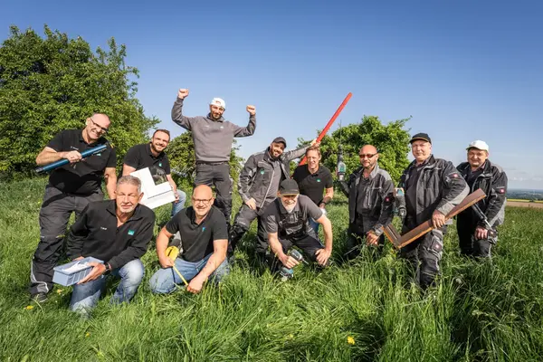 Team von Handwerkern mit Werkzeugen auf Wiese, Gruppenfoto im Freien