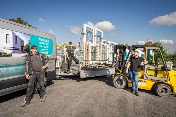 Monteure liefern Fenster und Türen mit Gabelstapler und Transporter aus.
