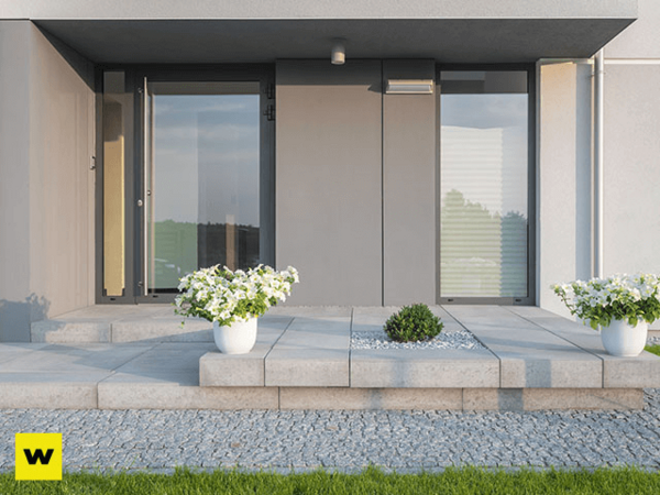 Moderner Hauseingang mit großen Glasflächen, Betonstufen und Blumenkübeln im Vorgarten.